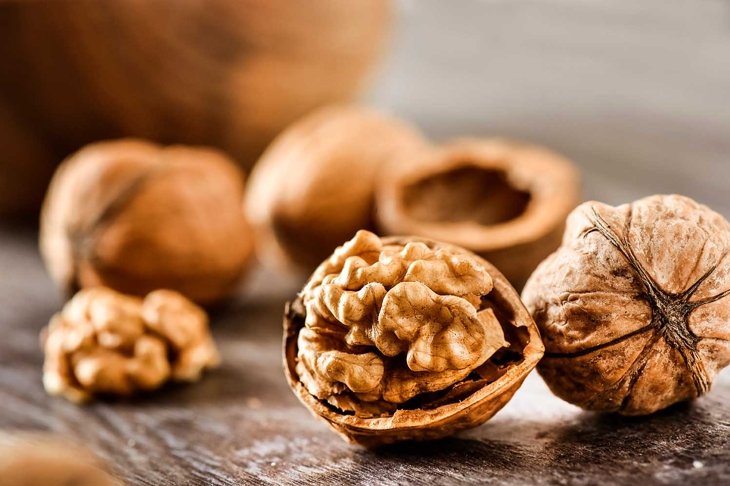 Walnuts kernels on dark desk with color background, Whole walnut in wood vintage bowl.