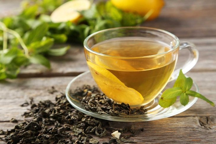 Cup with green tea on grey wooden background