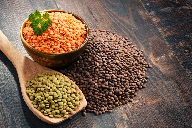 Composition with bowl of lentils on wooden table.