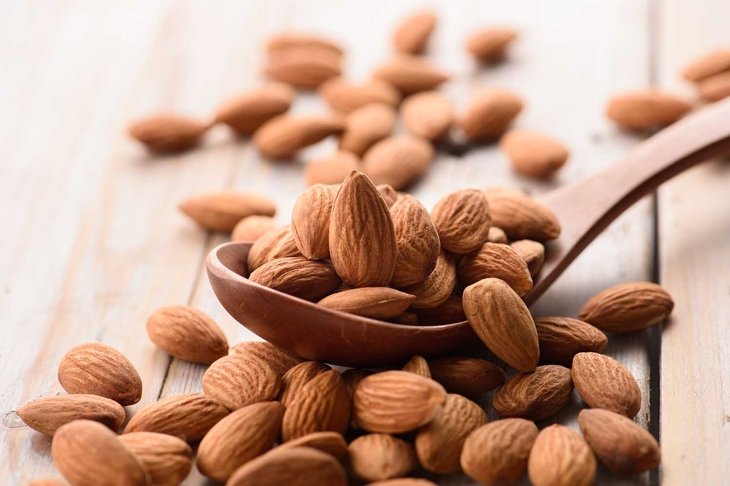 Almonds pour from wood spoon