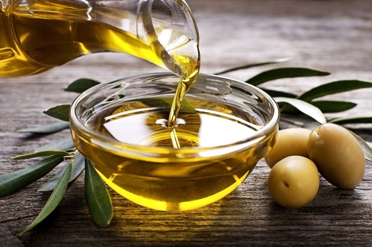 Bottle pouring virgin olive oil in a bowl close up