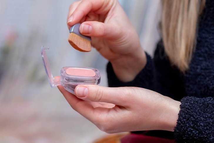 Young girl holding a box of powder and a blush brush