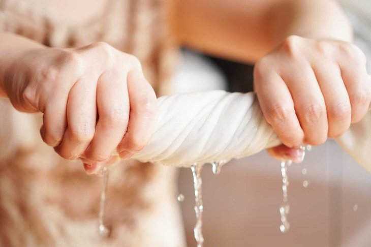 Two woman hands wring wet cloth after washing by twist and squeeze. Housework ,laundry and optimization concept ,selective focus on hand on the left